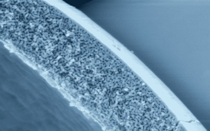 Light-blue-tinted ARC Hitachi SEM of the porous wall of a hollow glass microsphere, cropped for the homepage hero
